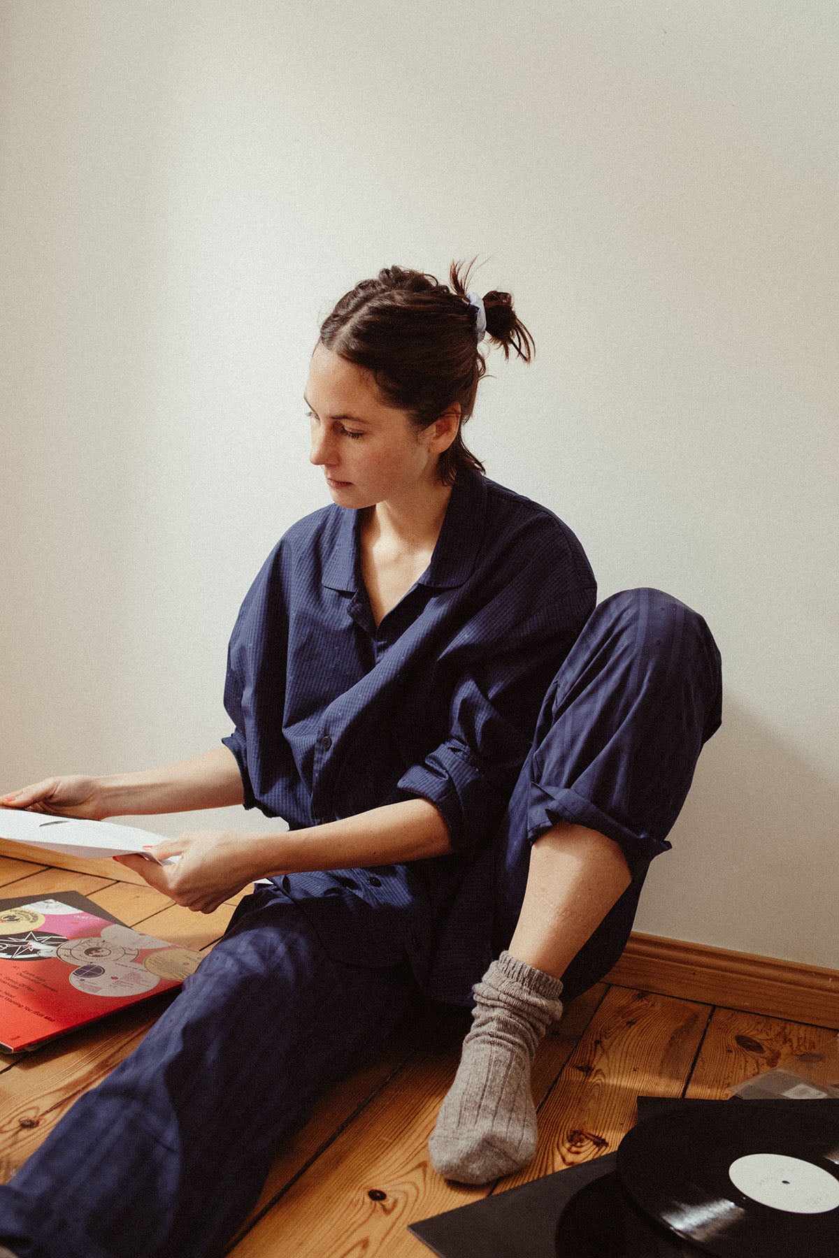 model sits on the floor in sustainable longsleeved pyjamas and checks her records
